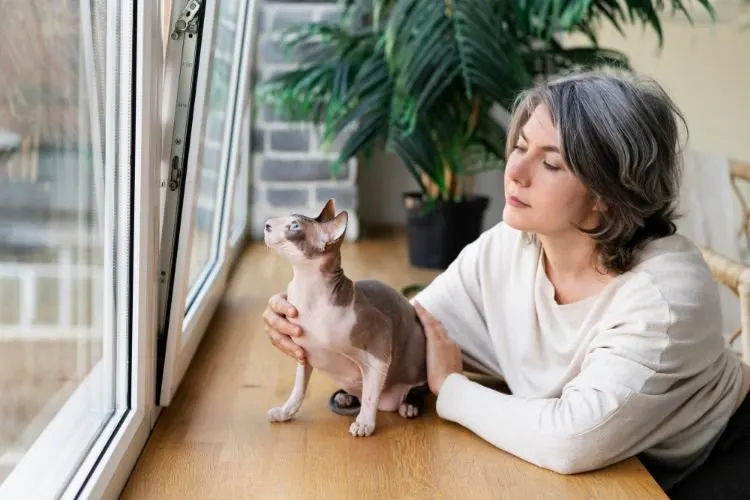 A woman sitting by a window with her dog